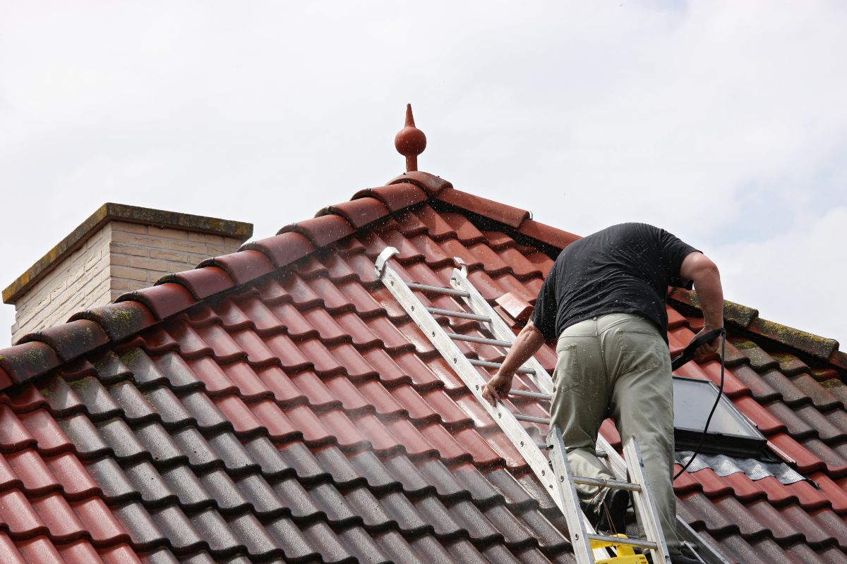 Professional roofer accessing roof via ladder